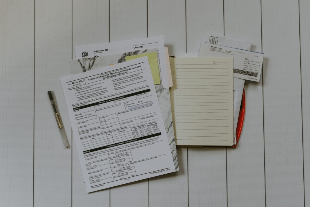 a stack of paperwork to use for taxes and rental property deductions laying on a white wooden surface